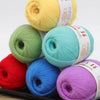 A collection of brightly colored fine yarn skeins in yellow, green, blue, and purple arranged on a dark tray.