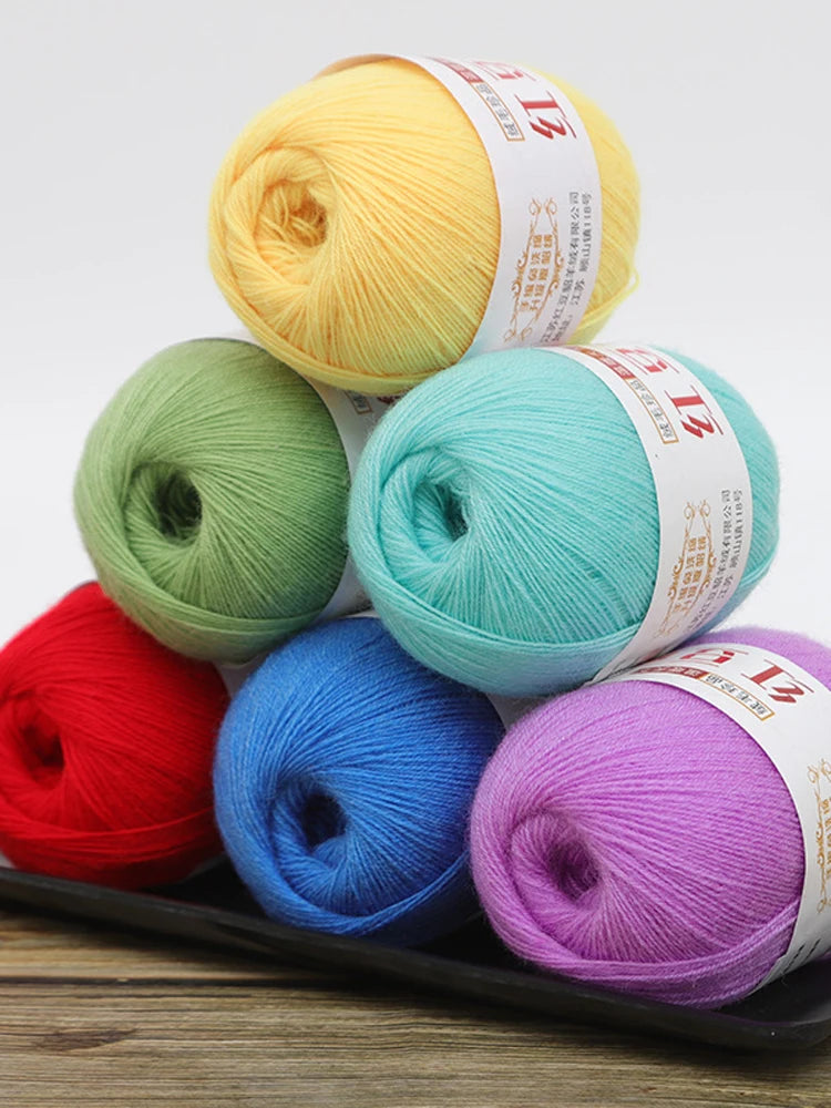 A collection of brightly colored fine yarn skeins in yellow, green, blue, and purple arranged on a dark tray.