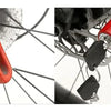 Close-up of a red anti-theft disc brake lock attached to a bicycle wheel.