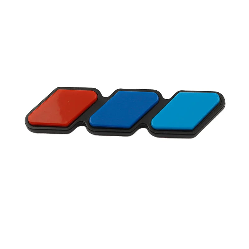 A set of three colored, rectangular grille emblem stickers in red, blue, and black.