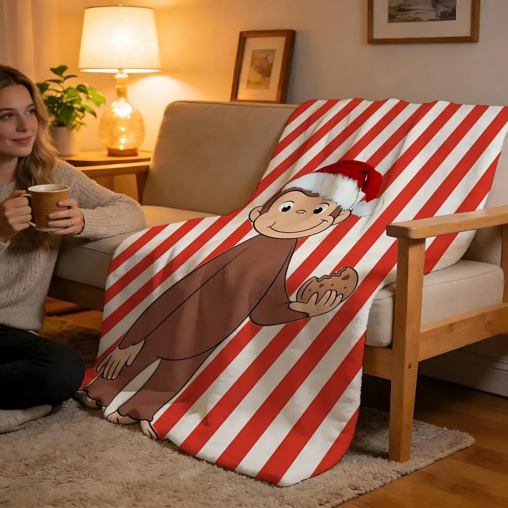 A cozy red and white striped throw blanket featuring a cartoon monkey design draped over a light-colored sofa.