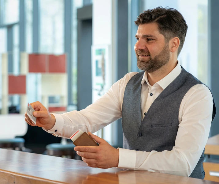 Un homme tient un portefeuille de carte en cuir véritable avec blocage RFID dans sa main.