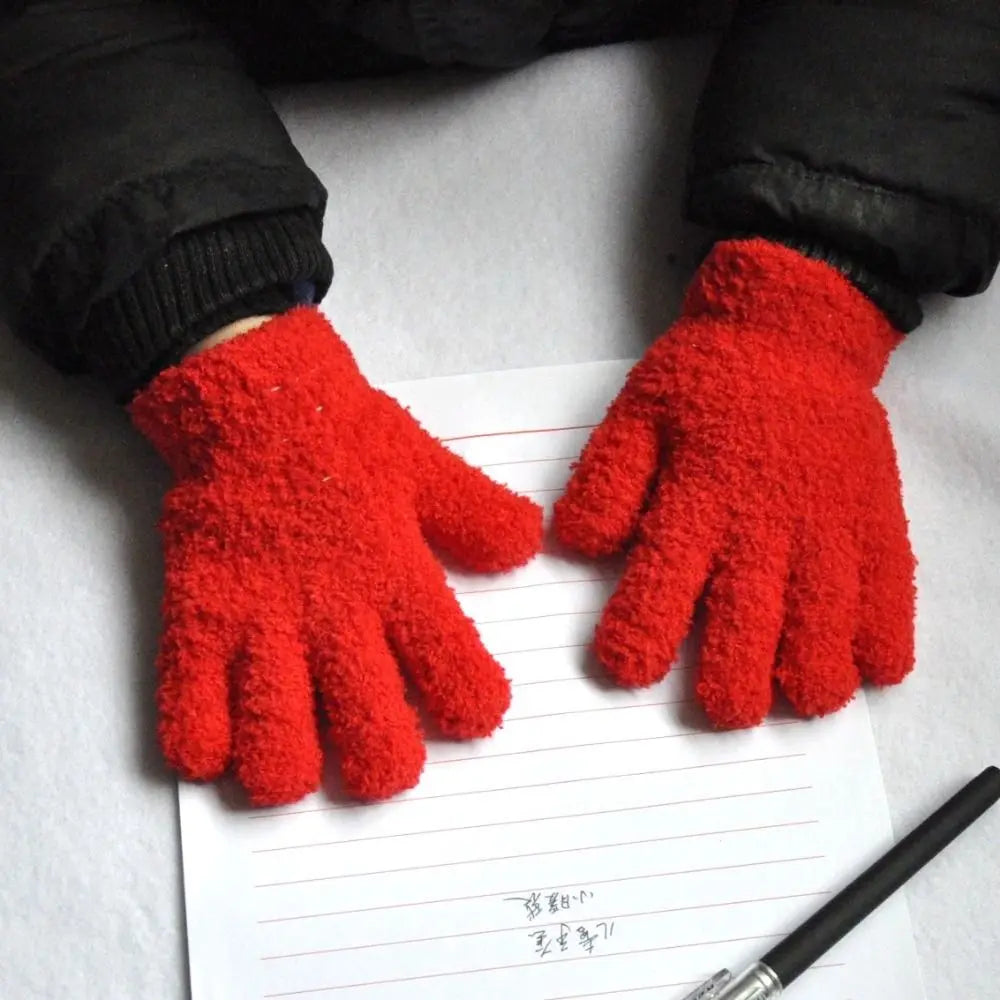 A pair of bright red, fuzzy plush winter gloves resting on lined paper.