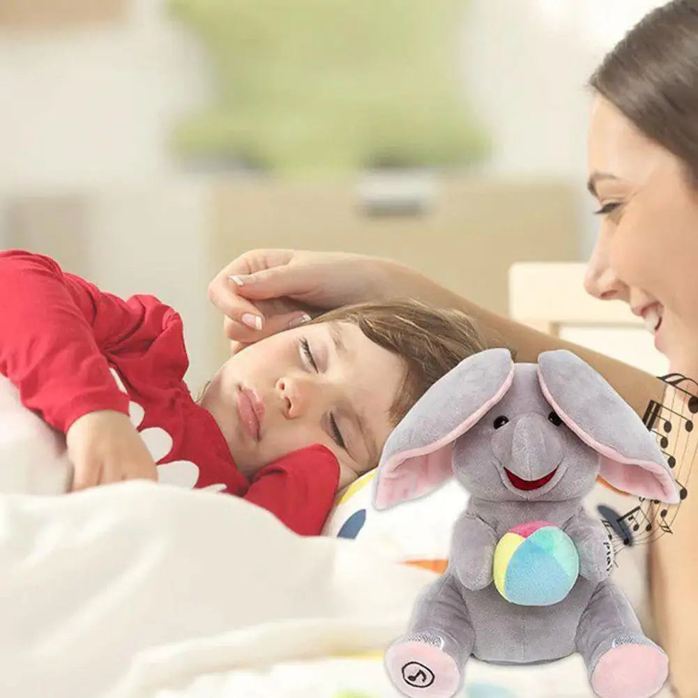 A young child is looking at an elephant plush toy with large ears and a colorful ball, held by an adult.