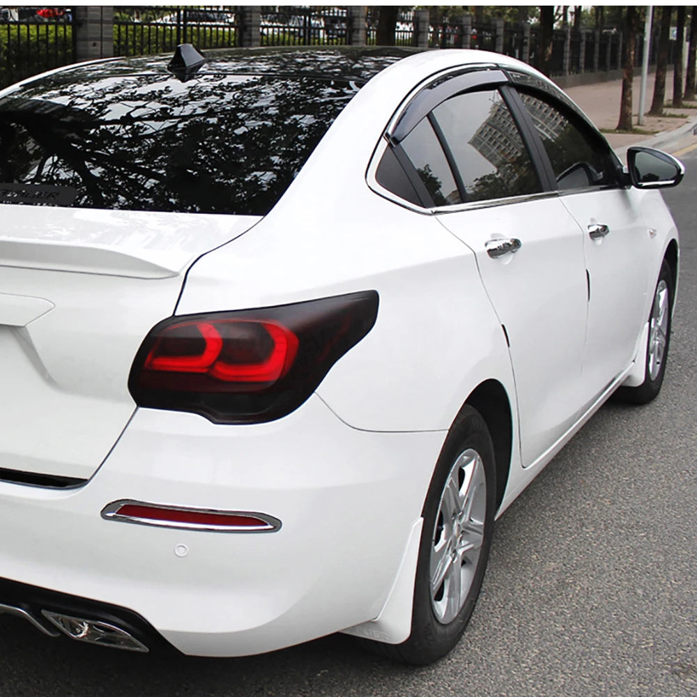 A white sedan with matte smoke tinted taillights and headlights parked on asphalt.
