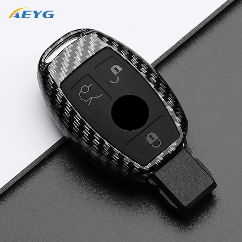 A black slim carbon fiber car key cover with various buttons and a cutout for a key.