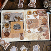 A page from a journal featuring vintage alchemy washi stickers, metal-embossed decorative elements, and small antique-style o