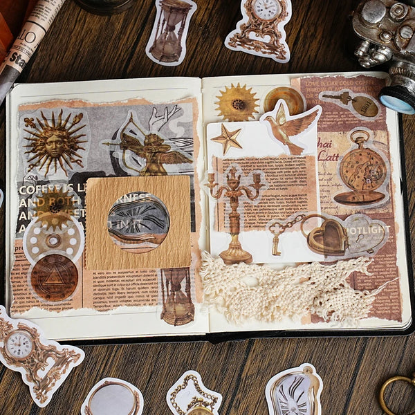 A page from a journal featuring vintage alchemy washi stickers, metal-embossed decorative elements, and small antique-style o