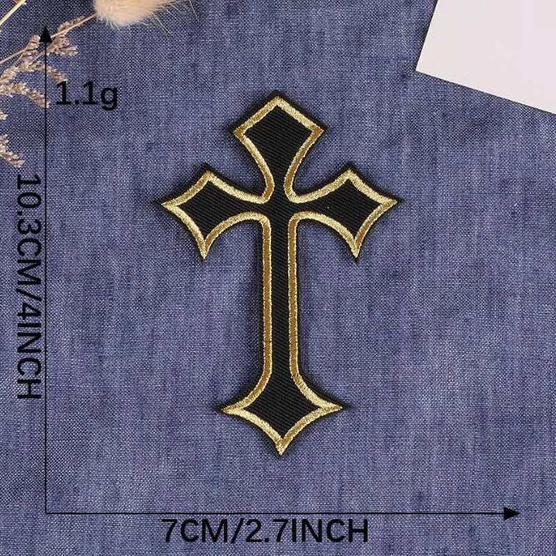 A black and gold embroidered cross patch on a denim fabric background.