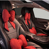Red butterfly bow tie neck pillows resting in the leather interior of a car seat.