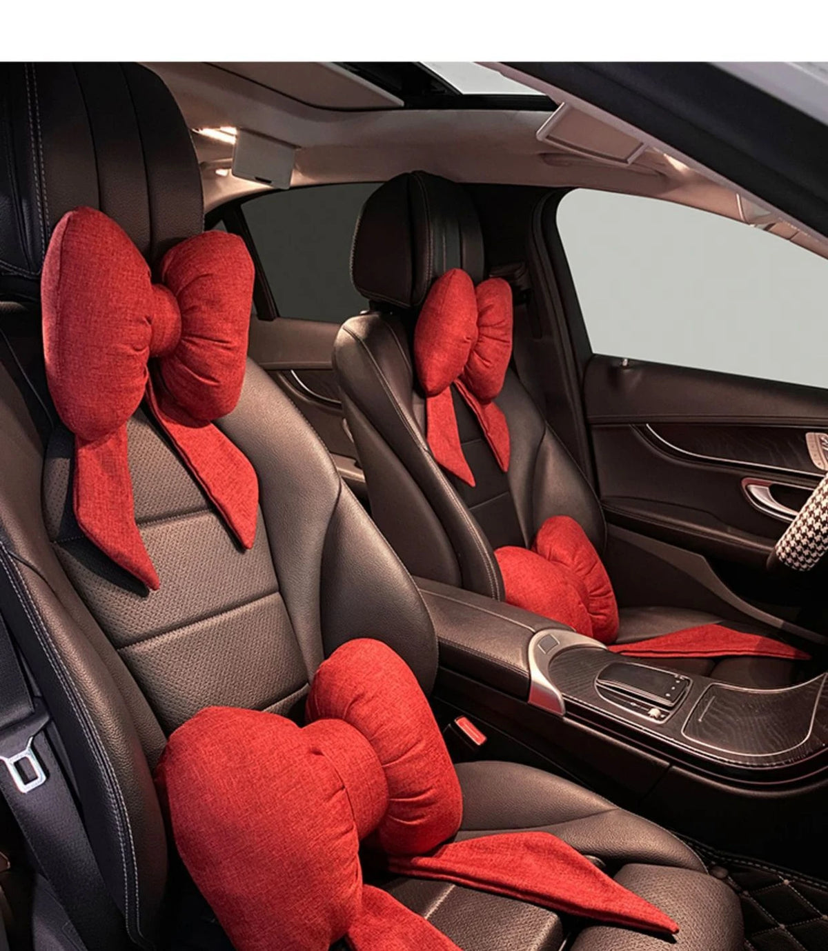Red butterfly bow tie neck pillows resting in the leather interior of a car seat.