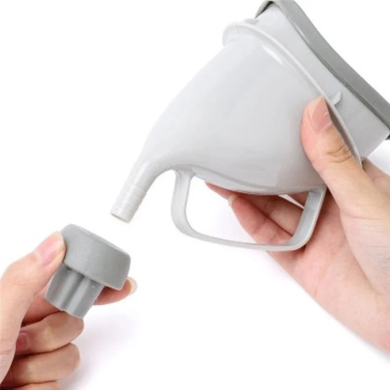 A hand is holding a portable reusable urinal funnel, which is gray and designed for travel or camping.