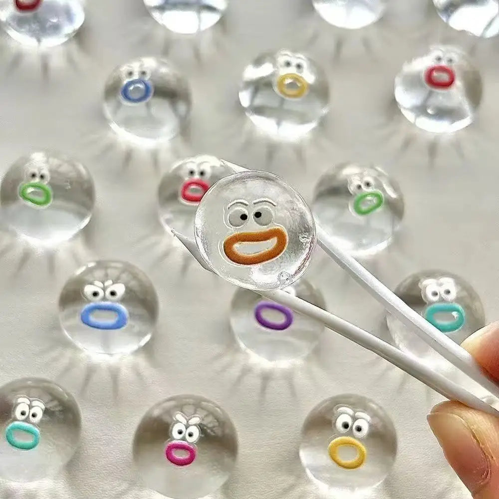 A collection of clear silicone fidget balls with various facial expressions and colors, illuminated by bright light.