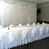 Elegant ice silk table skirt with matching top swag draped in white fabric.
