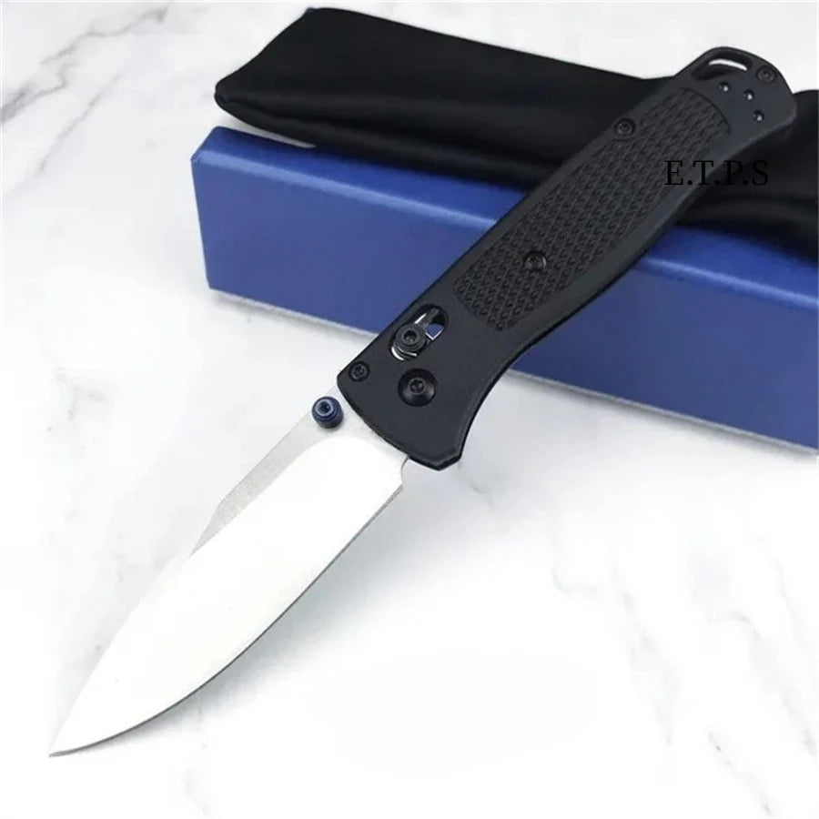 A black folding pocket knife with a drop point blade resting on a blue box.