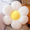 A white and yellow lifelike sunflower plush pillow with soft furry texture resting on a wooden surface.