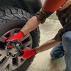 A person wearing red gloves is working on a tire wheel with a large off-road tire.