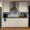White kitchen cabinets with a speckled countertop and a stainless steel hood above them.