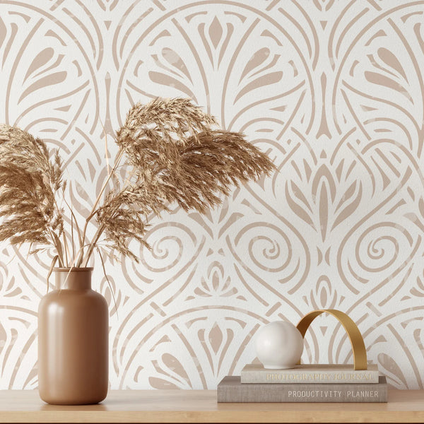 A vase of dried grasses sits on a wooden surface against a patterned wall with geometric white and beige designs.