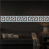 A horizontal acrylic mirror wall sticker featuring a geometric maze pattern mounted on a dark wall above a sofa.