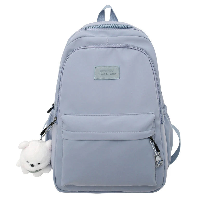 A light blue waterproof nylon laptop backpack featuring a small white plush toy attached to the zipper.