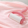 A pink silicone bath brush is shown resting on a soft pink towel.