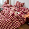 A plaid duvet cover in maroon and beige tones with a checkered pattern, featuring numerous pillows.