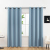 A pair of light blue blackout curtains hanging on a rod in a bright room.