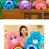 Tres juguetes de peluche Care Bear de colores arcoíris de pie en un estante de madera.