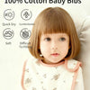 A baby is wearing a white cotton bib with a pink trim, sitting on a light background.
