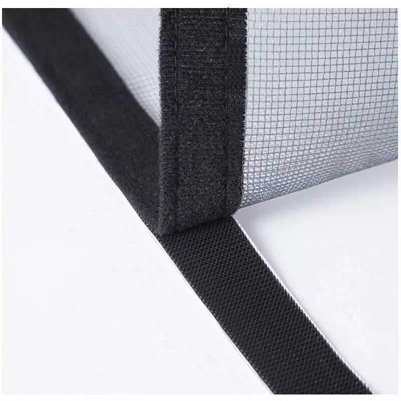 Close-up view of a black self-adhesive window mosquito net screen being applied to a window frame.