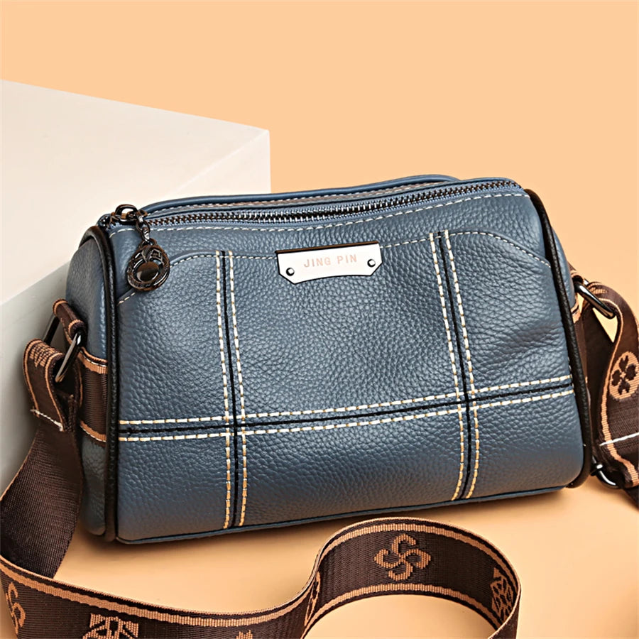 A dark blue vintage genuine leather women's shoulder bag with gold stitching and a brown leather strap.
