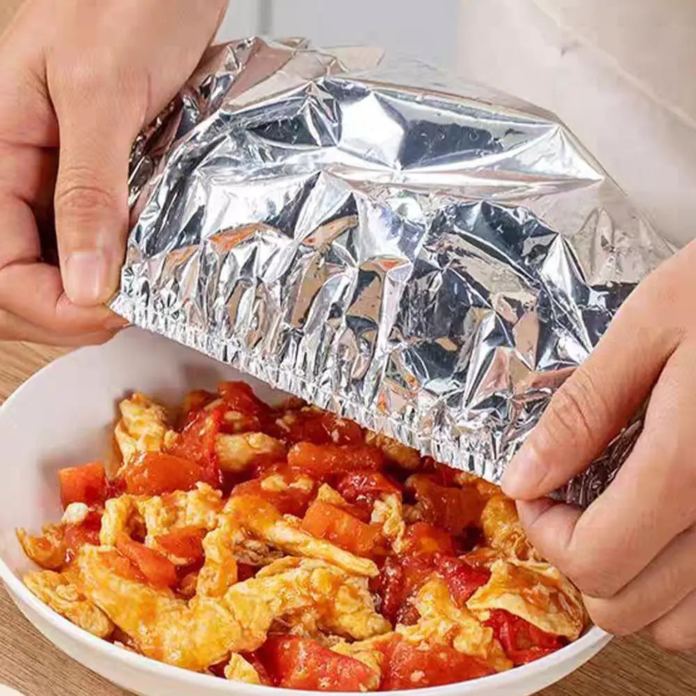 Hände öffnen einen wiederverwendbaren Aluminium-Essbehälter, um gebratenes Rührei mit Tomaten zu zeigen.