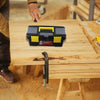 A black and yellow plastic toolbox is placed on a wooden workbench with a hand nearby.