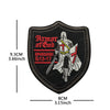 Black embroidered patch shaped like a shield featuring a cross and text from Ephesians 6:13-17