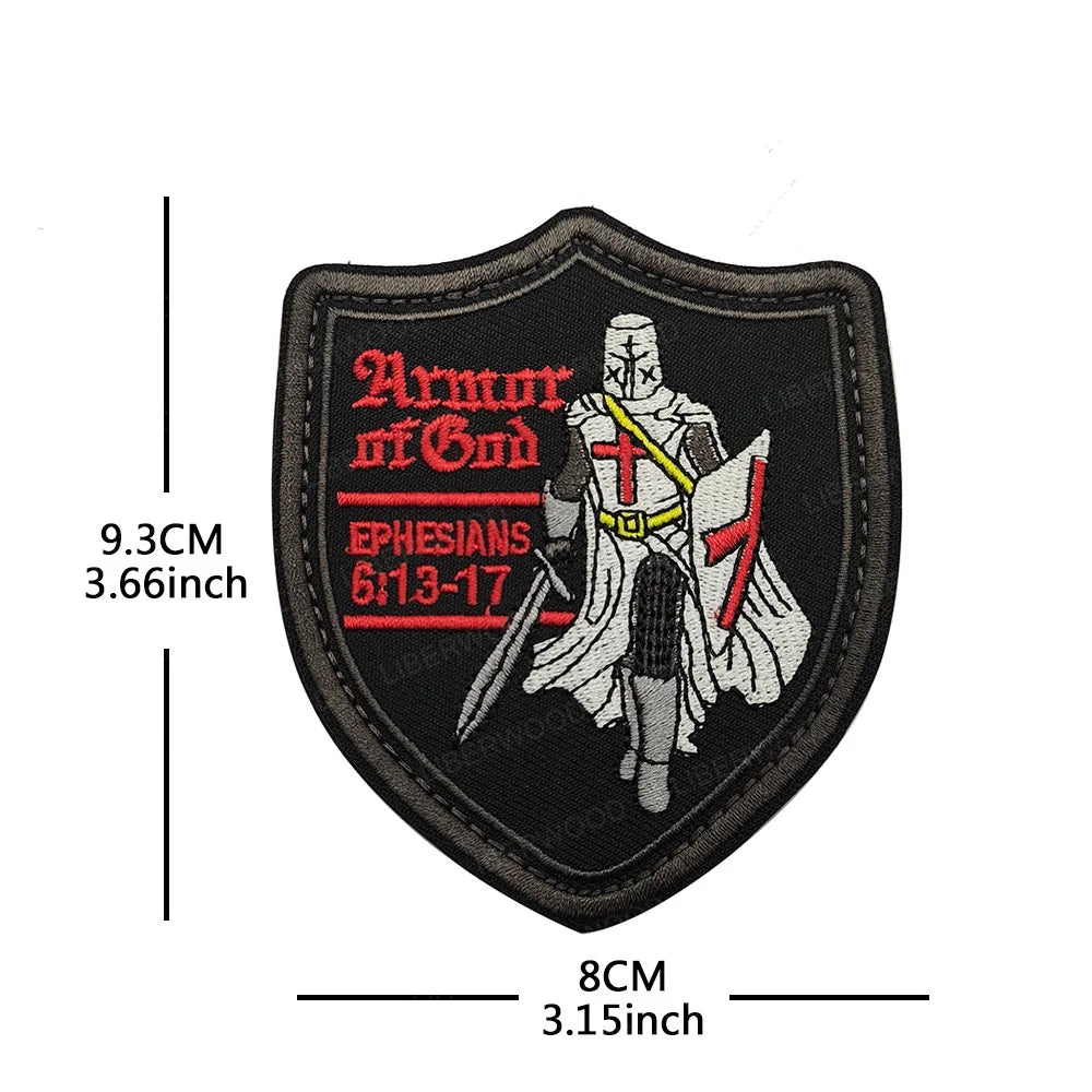 Black embroidered patch shaped like a shield featuring a cross and text from Ephesians 6:13-17