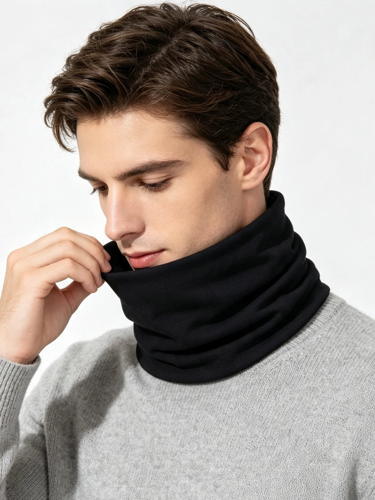 A man wearing a black neck warmer scarf over a gray sweater.