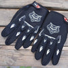 A pair of black full finger nylon riding gloves with anti-slip grips resting on a wooden surface.