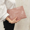A woman holds a pink crocodile-embossed PU leather envelope clutch against a light background.