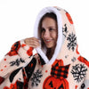 Eine lächelnde Frau in einem gemütlichen, lappigen Oversize-Fleece-Hoodie mit orange-schwarzem Schneeflockenmuster.
