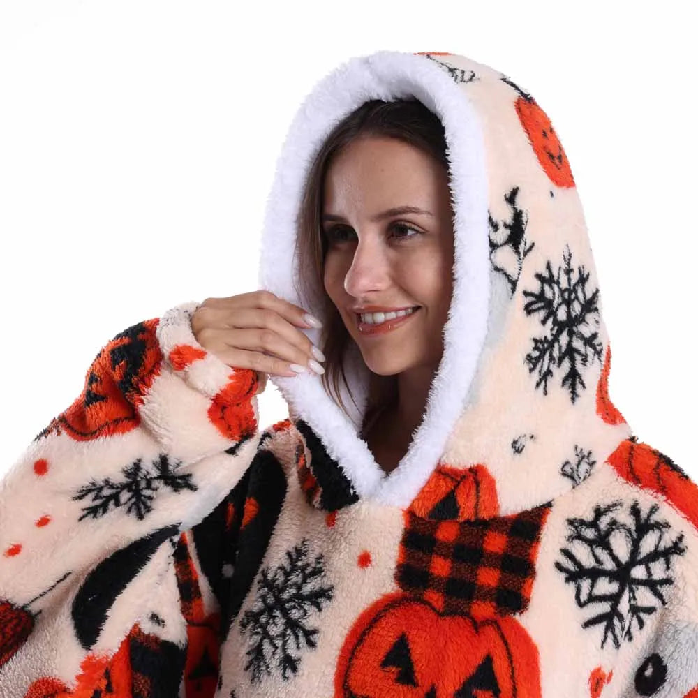 Eine lächelnde Frau in einem gemütlichen, lappigen Oversize-Fleece-Hoodie mit orange-schwarzem Schneeflockenmuster.