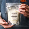 A hand holds a clear plastic bag containing white natural soybean wax flakes for DIY candle making.