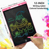 A hand holds a 12-inch pink LCD writing tablet displaying a green drawing of Santa Claus and presents.