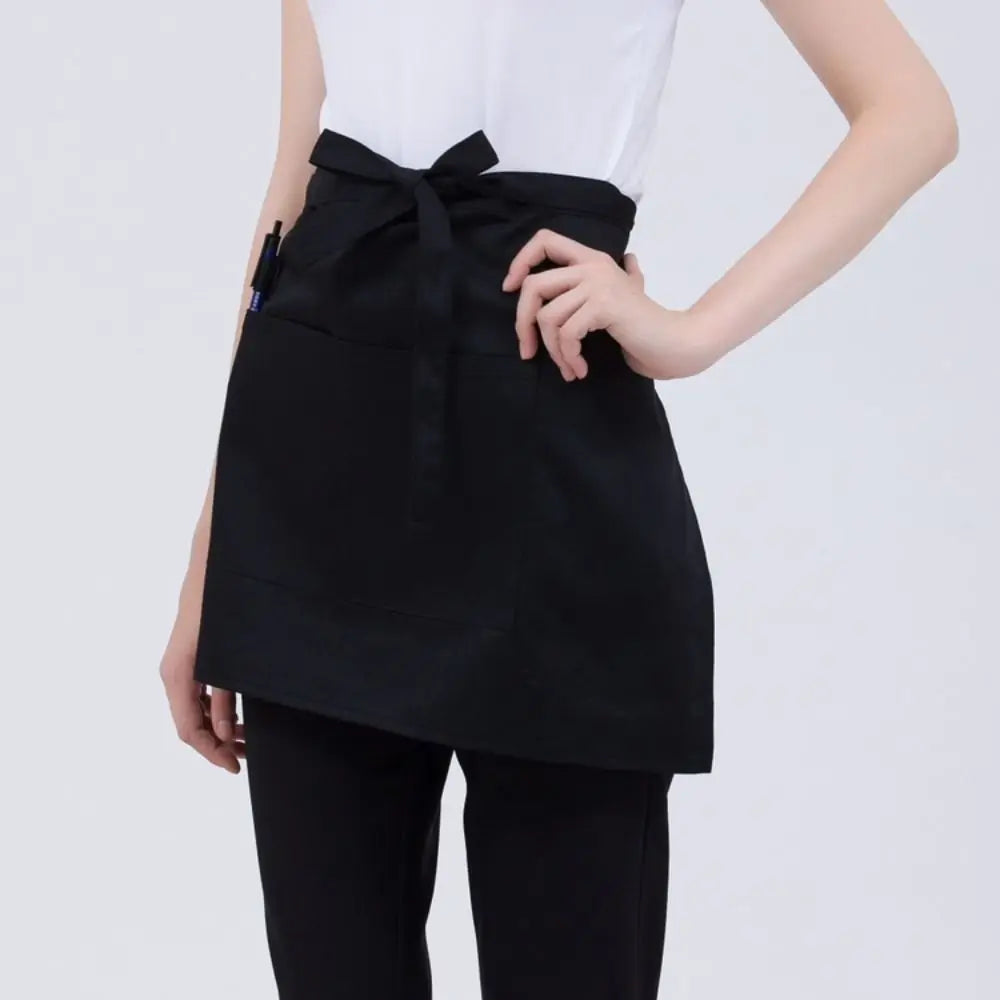 A black classic half apron with pockets is shown being worn by a person.