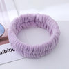 A purple microfiber wrist sweatband and scrunchies for face washing is shown on a white surface.
