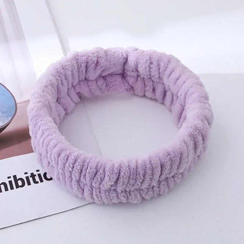 A purple microfiber wrist sweatband and scrunchies for face washing is shown on a white surface.