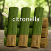 Green citronella incense sticks standing upright in a wooden container.