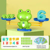 A green frog balance math learning toy with a happy face and various cards for children.