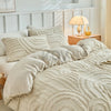 Beige besticktes Blumen-Duvetcover-Set auf einem Bett mit neutraler Bettwäsche und Beistelltisch aus Holz.