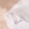 A white, folded baby burp cloth is shown in soft natural light.